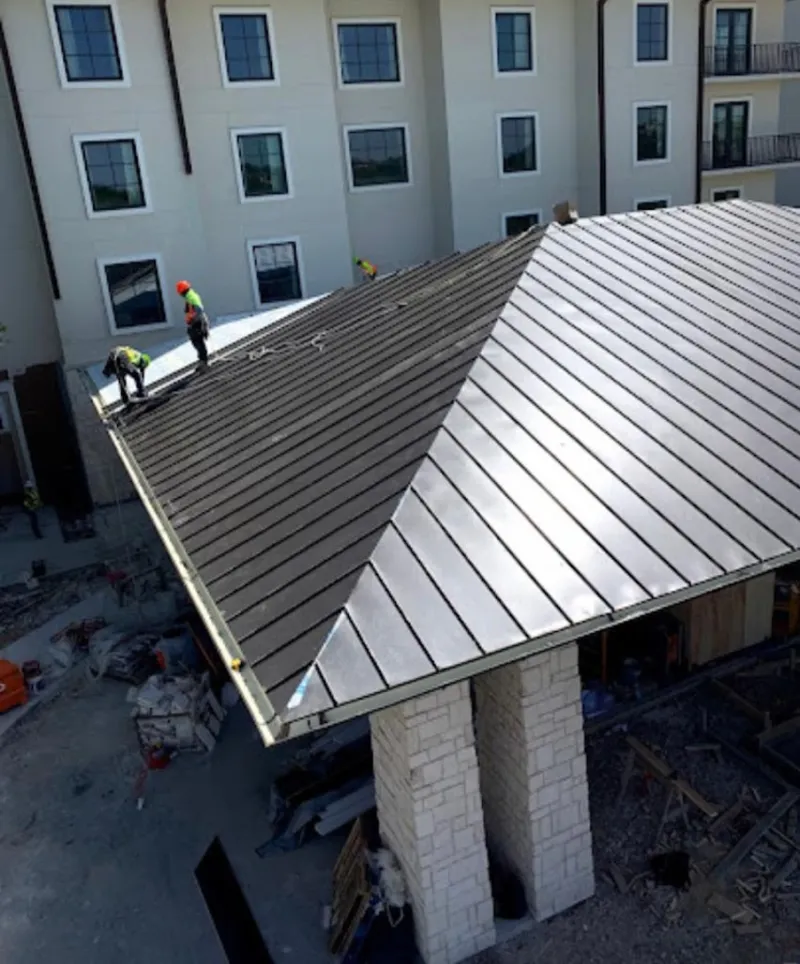 Crew installing standing seam metal roof panels on a commercial project in Union